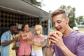 Happy man with hamburger and friends at food truck
