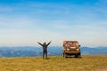 Happy man with hands up travel by car on mountains top Royalty Free Stock Photo