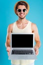 Happy man in hat and sunglasses holding blank screen laptop Royalty Free Stock Photo