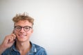 Young beautiful smiling hipster guy talking on mobile phone, standing against wall with copy space. Royalty Free Stock Photo