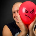 Happy man hiding behind angry balloon Royalty Free Stock Photo