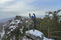 Happy man hiker standing at mountain top and celebrates success in winter day