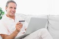 Happy man on his couch using laptop for shopping online Royalty Free Stock Photo