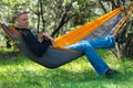 Happy man with his funny dog relaxes in a hammock