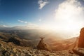 A happy man with his hands up high stands on top of a separately standing rock that is above the clouds against the Royalty Free Stock Photo