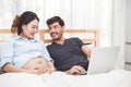 Happy man and his pregnant wife using laptop to searching newborn baby items for preparing parenthood. Couple lifestyle family and Royalty Free Stock Photo