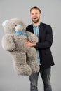 Happy man hold grey teddy bear. Macho smile with big animal toy. Thisi is for you. Gift and present concept. Birthday Royalty Free Stock Photo