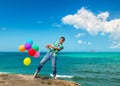 Happy man holding bunch of colorful air balloons at the beach Royalty Free Stock Photo