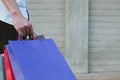 happy man holding colorful shopping bag outdoors. shopaholic male walking in city. shopper enjoy buying. consumerism concept