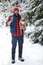 Happy man holding lovely dog in his hands in snowy forest. Smiling boy hugging adorable puppy in winter wood. Pet lover Royalty Free Stock Photo