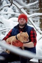 Happy man holding lovely dog in his hands in snowy forest. Smiling boy hugging adorable puppy in winter wood. Pet lover Royalty Free Stock Photo