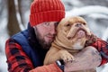 Happy man holding lovely dog in his hands in snowy forest. Smiling boy hugging adorable puppy in winter wood. Pet lover Royalty Free Stock Photo