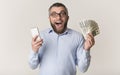 Happy man holding smartphone and showing bunch of money