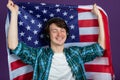 Happy man holds an American flag and listens to music with headphones on a purple background Royalty Free Stock Photo