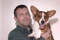 A happy man holds a beautiful corgi dog in his arms. A dog is a man`s friend Royalty Free Stock Photo