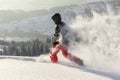 Happy Man with hood running in deep powder snow with snowshoes. Snow is spraying and splashing.