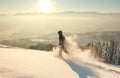 Happy Man with hood running in deep powder snow with snowshoes at sunrise. Snow is spraying and splashing. Allgau Alps Royalty Free Stock Photo