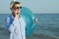 Happy man with inflatable ring talking by mobile phone near sea on beach. Business trip Royalty Free Stock Photo