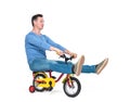 Happy man in jeans and t-shirt on a children`s bike, isolated on white background. Royalty Free Stock Photo