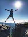 Happy Man jumping above cracked sandstone cliff. Travel style