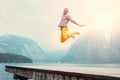 Happy man jumps on wooden pier at the mountain lake Royalty Free Stock Photo