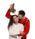 Happy man kissing his girlfriend under mistletoe bunch on white background Royalty Free Stock Photo