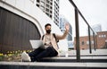 Happy man with laptop using laptop on the way to work outdoors in city, coronavirus concept. Royalty Free Stock Photo