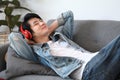 Happy man listening music with wireless headphone and lying on couch at home. Royalty Free Stock Photo