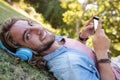 Happy man lying on grass listening to music on mobile phone Royalty Free Stock Photo
