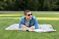 Happy Man Lying On Green Grass and study remotely. Adult man rest in the park. Smiling man working on outdoor Royalty Free Stock Photo