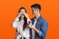 Happy man makes surprise and gives ring in red box, woman covers her eyes with hands Royalty Free Stock Photo