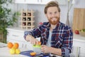 happy man making orange juice in kitchen at home Royalty Free Stock Photo