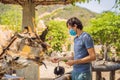 Happy Man In Medical Mask Watching And Feeding Giraffe In Zoo. He Having Fun With Animals Safari Park On Warm Summer Day