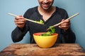 Happy man mixing salad with wooden spoons