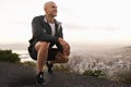 Happy man, mountain and fitness with view of city for workout, exercise or training in nature. Young male person or Royalty Free Stock Photo