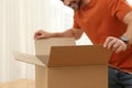 Happy man opening parcel, closeup. Internet shopping