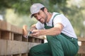 happy man painting wooden fence in garden sitting