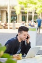 Happy man on phone call with laptop at cafe Royalty Free Stock Photo