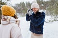 happy man photographing woman in winter forest