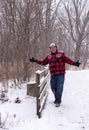 Happy man walking across a wooden bridge in the snow