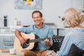happy man playing acoustic guitar and looking at senior wife Royalty Free Stock Photo