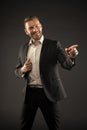 Happy man point finger on dark background. Bearded man smile in formal suit. Businessman with beard and hairstyle