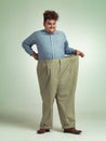 Happy man, portrait and plus size with pants for waist, weight loss or measurement on a studio background. Male person Royalty Free Stock Photo