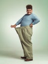 Happy man, portrait and plus size with weight loss or pants for measurement or waist on a studio background. Male person Royalty Free Stock Photo