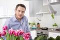 Happy man posing in the kitchen with pink tulips Royalty Free Stock Photo