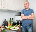 Happy man in the prime of life in kitchen prepared two salads Royalty Free Stock Photo