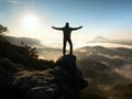 Happy man with raised arms gesture triumph on exposed cliff. Satisfy hiker