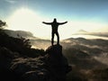 Happy man with raised arms gesture triumph on exposed cliff. Satisfy hiker