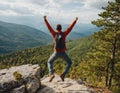 Happy man with raised arms jumping on top of mountain. Successful tourist celebrates success on a rock. Royalty Free Stock Photo