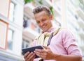 Happy man reading latest news articles from tablet PC while being outdoors on city street. Tablet PC in his hands allows Royalty Free Stock Photo